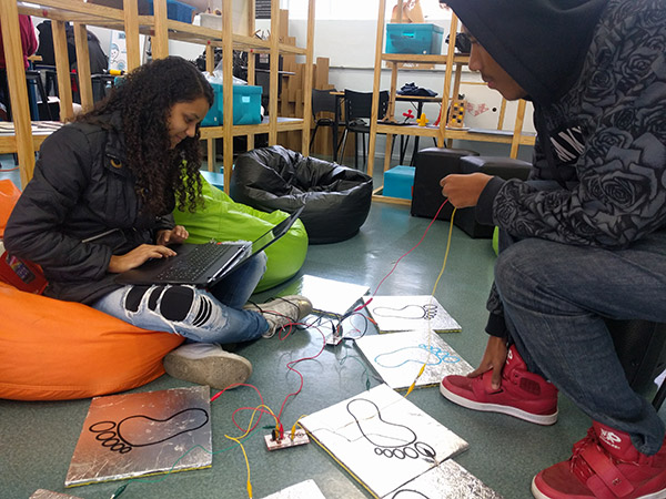 Dois alunos finalizando as configurações com chapas de alumínio, circuitos notebook